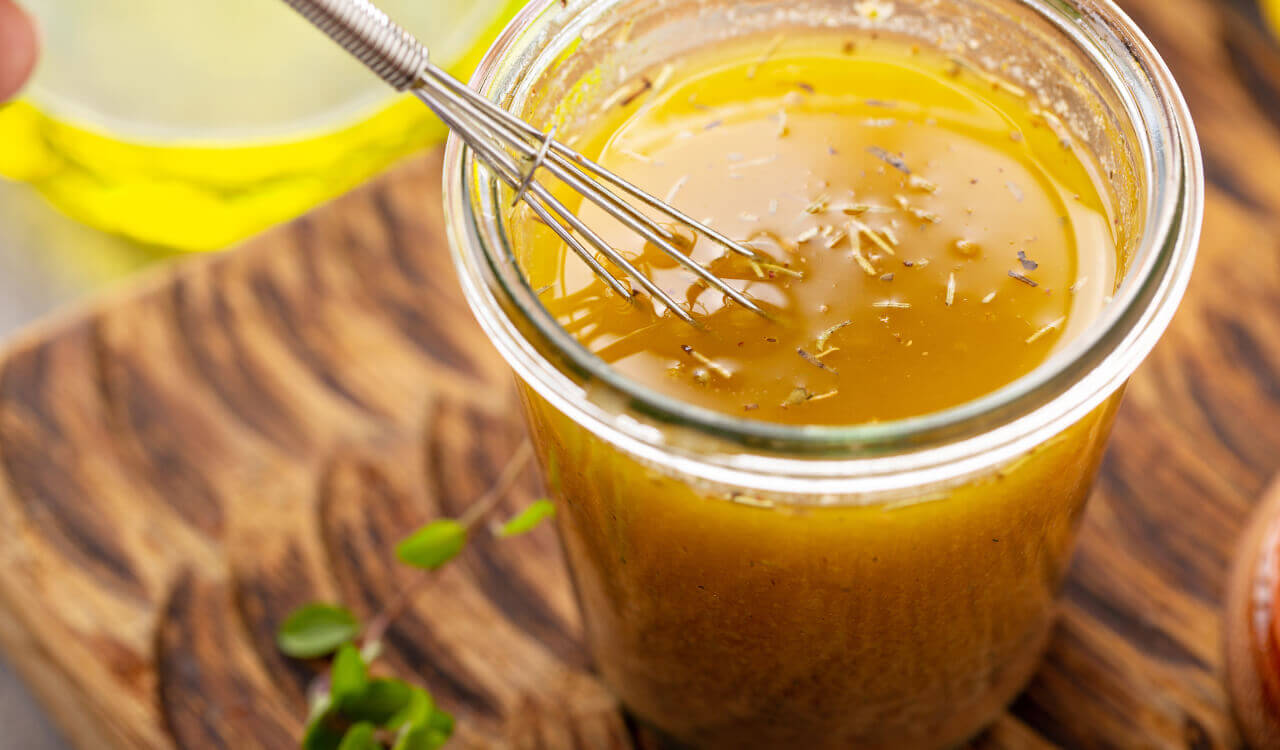 dressing being poured into a bowl of salad