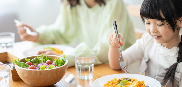 A kid and her mom are enjoying vegetables together